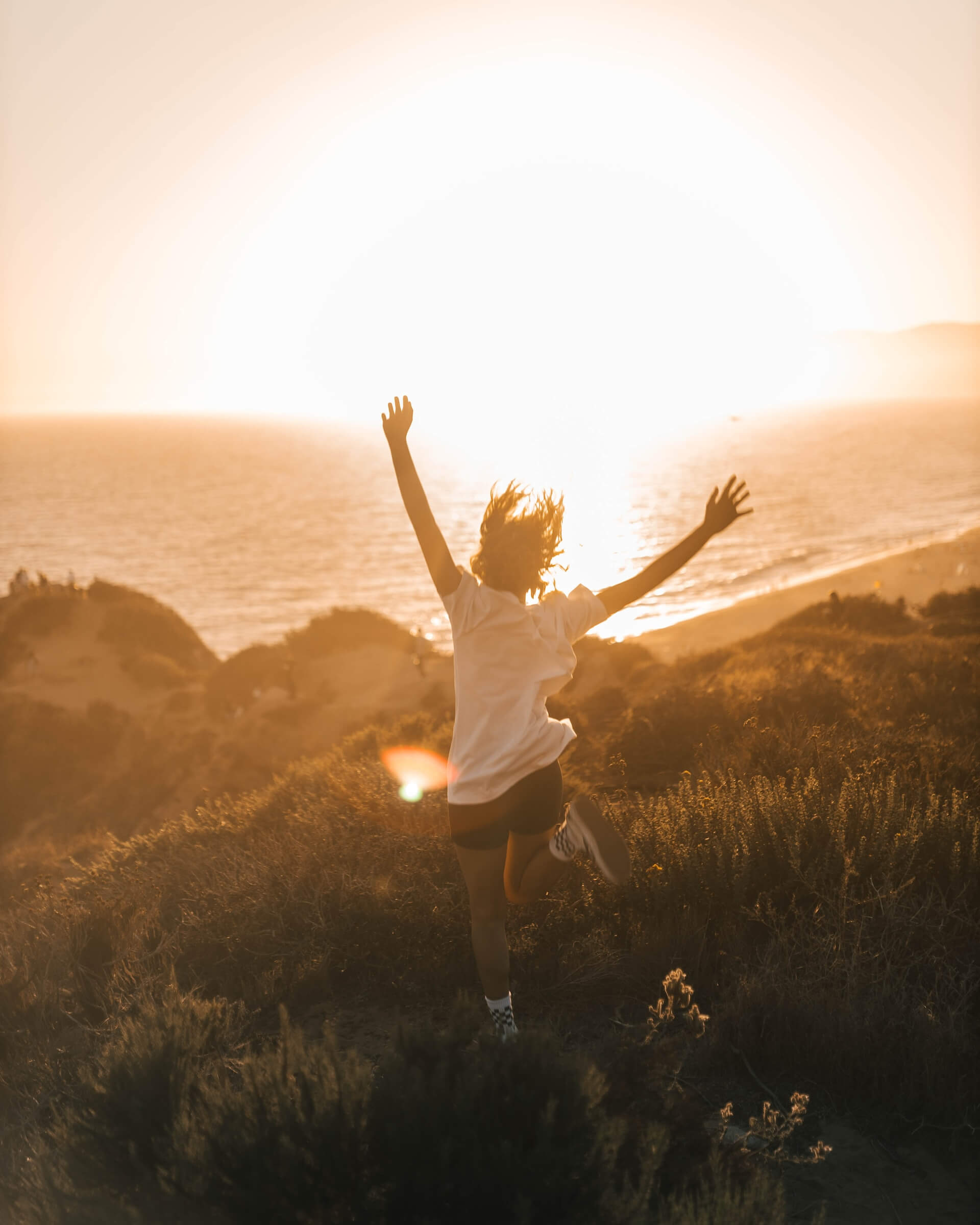 A person jumping up in the air near the ocean